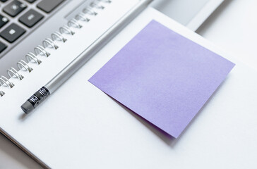 Notebook, laptop, stickers, paper clips in the workspace on the table in the office.