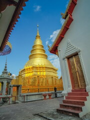 Naklejka premium view of Phra That Haripunchai, The Golden Pagoda (stupa, Chedi) with blue sky background, Wat Phra That Haripunchai Woramahawihan, Lamphun Province, northern of Thailand.