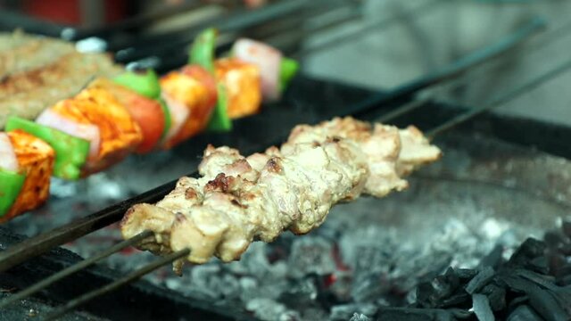 Roasting cooking chicken malai tikka on an Indian charcoal grill. Closeup of chicken.