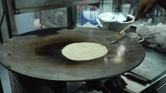 Cooking Indian bread parantha on a huge Indian pan at a street food restaurant. 