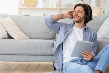 Joyful man listening to music, sitting on floor at home