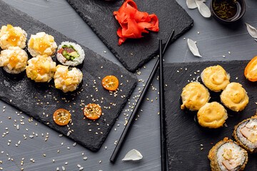 Set of sushi rolls, sauce, wasabi and hand with chopsticks on dark background. Top view. Flat lay. Japanese food