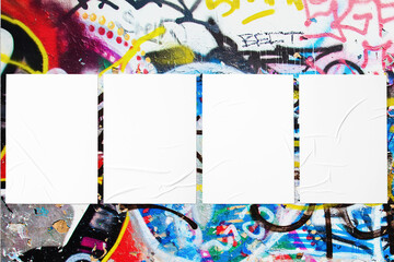 Closeup of colorful messy painted urban wall texture with four wrinkled glued poster templates....