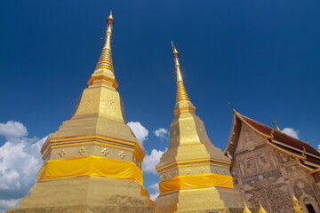 Fototapeta premium view of ancient golden pagoda (Phra Phutthabat Huai Tom) with blue sky background, Wat Phra Phutthabat Huai Tom, Li District, Lamphun, northern of Thailand.