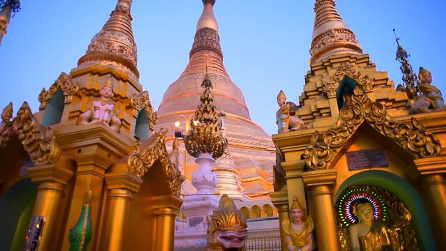 Tilt up shot of statues by golden pagodas against sky - Yangon, Myanmar