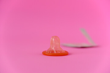 opened red condom with condom pack on pink paper background with copy space for text. Reproductive...