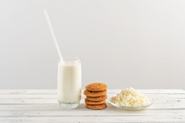 milk in a glass goblet with straw on a white background. stack of oatmeal cookies and cottage cheese