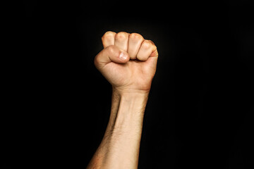 Male fist on a black background. Aggressiveness, masculinity, the concept of challenge