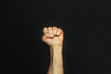 Male fist on a black background. Aggressiveness, masculinity, the concept of challenge
