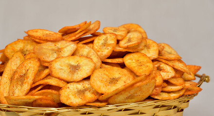 Banana chips from Kerala cuisine fried in coconut oil, Banana chips on a white golden bowl, spicy salty banana chips or wafers with herbs masala traditional indian gujarati snack