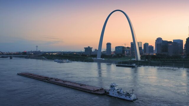 Aerial: The Gateway Arch, Barge on the Mississippi River & downtown St Louis at sunset, Missouri, USA