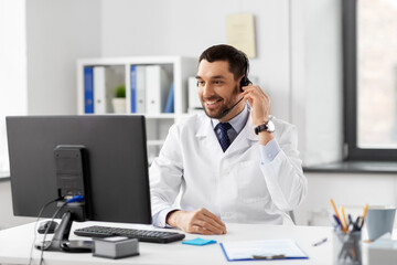 healthcare, medicine and technology concept - happy smiling male doctor with computer and headset working at hospital
