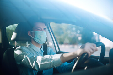 Young man  in protective sterile medical mask sits in the car during an epidemic in quarantine...