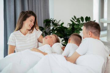 Young family enjoying at home. Happy parents with sons relaxing on sofa.	