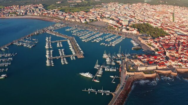 4k drone flight above footage (Ultra High Definition). Bright summer cityscape of Alghero port, Province of Sassari, Italy, Europe. Spectacular evening scene of Sardinia island, Mediterranean seascape