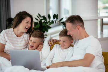 Young family watching movie on lap top. Beautiful parents with kids enjoying at home.	