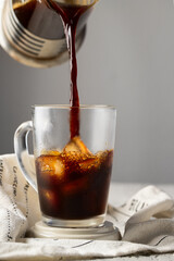 Coffee pouring into the glass cup with ice. Ice coffee concept.