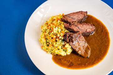 Sliced hanger steak with mashed potato with vegetable, sauce.