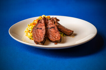 Sliced hanger steak beef with mashed potato with vegetable.