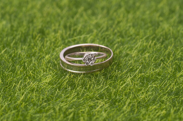 A pair of wedding/engagement ring isolated over green grass