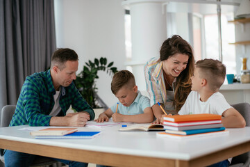 Parents helping the kids with their homework. Litlle boys learning at home.
