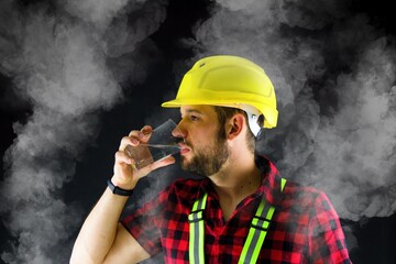 Tired Construction Worker drinks water.  There is dust everywhere.