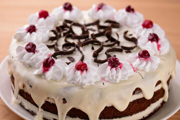 Chocolate vanilla cake with cherry jelly, topped with white cheese frosting and chocolate pieces