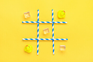 duck toy, ice cubes, paper tubes with blue stripes for drinks on a yellow background. Sea battle,...