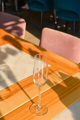 Transparent empty champagne glass on the rustic wooden table over blurred restaurant background.
