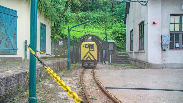 Yellow locomotive of train comes out of tunnel of mount Peca