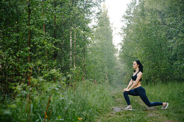 Athletic girl in leggings and top warming up in the woods