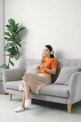 Obraz premium Serene young woman resting on sofa wearing casual home clothes wireless headphones enjoy weekend free time