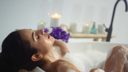 Close up sexy woman bathing at luxury home. Relaxed girl lying in foam bath.