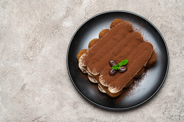 Classic tiramisu dessert on ceramic plate on light grey concrete background