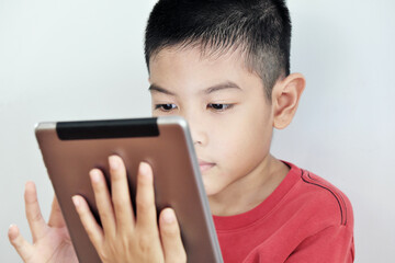 A boy playing a tablet on a white background