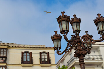 Fototapeta na wymiar Antique bronze lantern on the background of typical Spanish buildings.