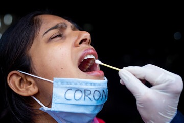 Doctor's hand taking Saliva test from young woman's mouth with Cotton Swab. Coronavirus Throat sample Collection. Close-up views.