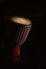 Djembe percussion partially illuminated on a black background