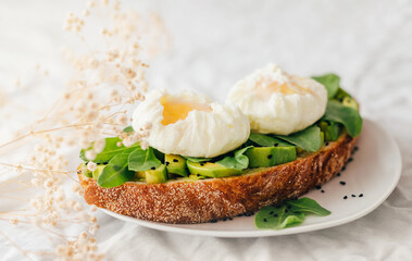 sandwich with avocado, arugula and poached egg sprinkled with nigella decorated with small...