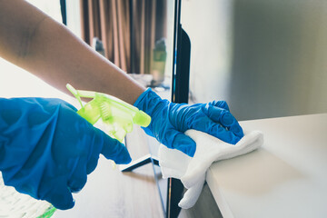 Cleaning surface furniture. Hand in blue rubber glove wiping surfaces disinfection spray bottle surfaces and wipes.