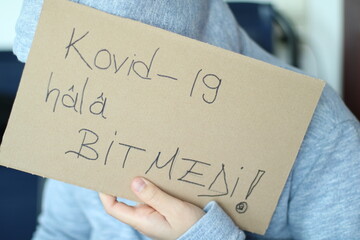 die frau hat einen karton in der hand, sie schreibt kovid auf den karton