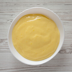 Homemade vanilla custard pudding in a white bowl, overhead view. Flat lay, top view, from above.