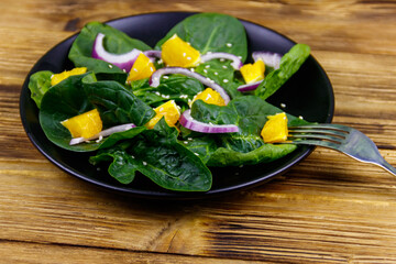 Tasty salad with spinach, orange, red onion and sesame seeds on wooden table. Healthy food or vegetarian concept