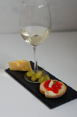 sandwiches with red caviar and belm wine on a black stone board
