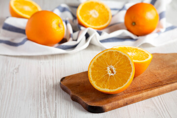 Halved and whole oranges on a white wooden surface, side view. Close-up.
