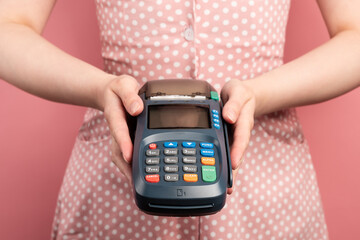 Woman in a pink dress hold NFC payment contactless terminal. Credit card or phone pay pos banking...