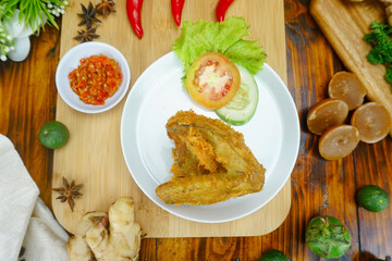 fried chicken wing with fresh vegetable on wooden board background