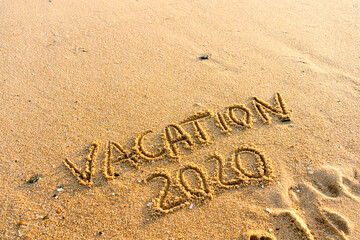 Fototapeta premium 2020 Vacation handwritten on sandy beach natural outdoors background.
