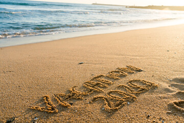 2020 Vacation handwritten on sandy beach natural outdoors background.
