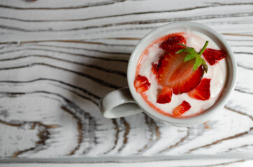 strawberry yogurt in a white cup with mint and fresh strawberries